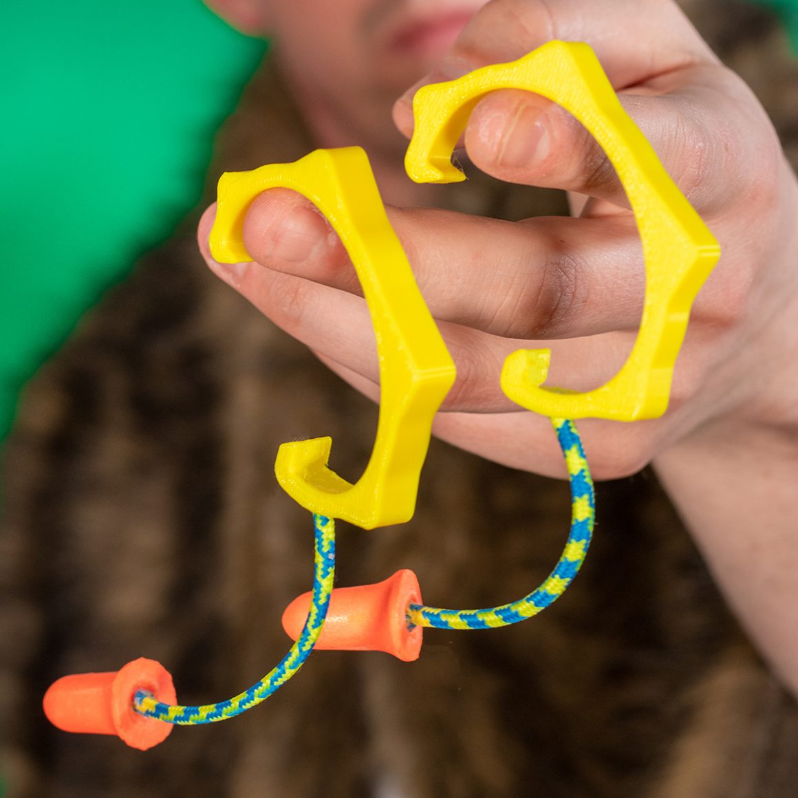 A yellow hand-held accessory with corded earplugs hanging below it.