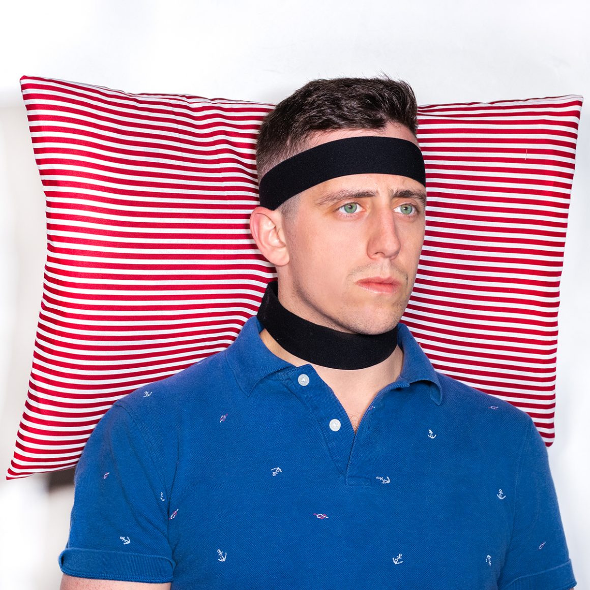 Matty wearing a red-and-white striped pillow behind his head with black straps.