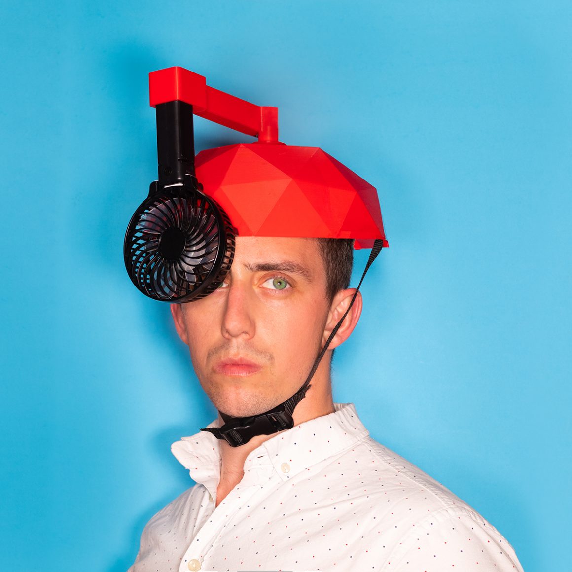 Matty wearing a red helmet with a black fan hanging beside his face.