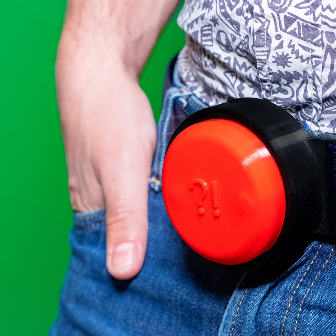 A large red push button set inside a black buckle at Matty’s waist.