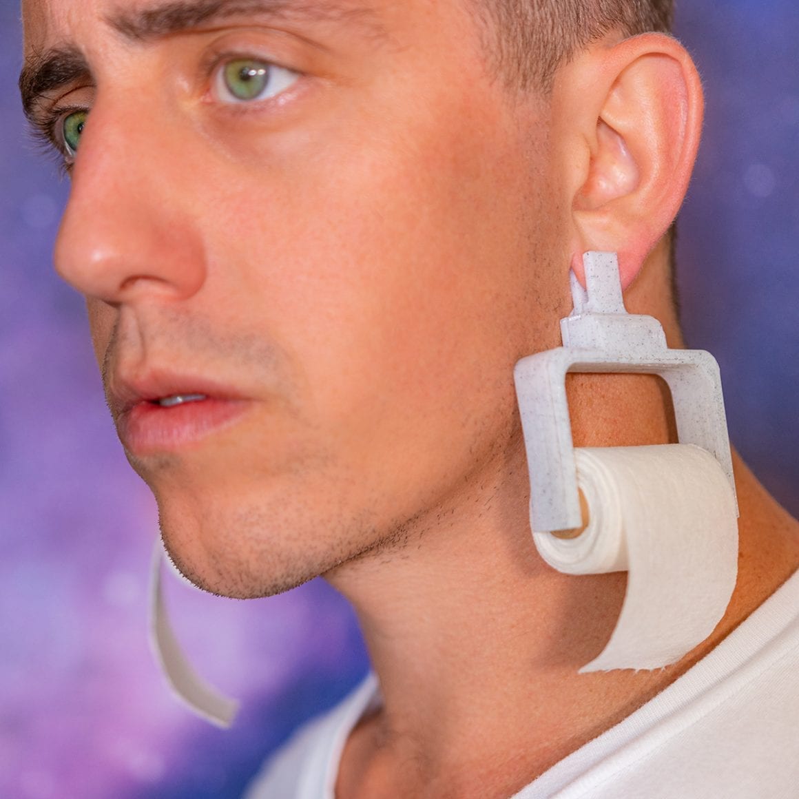 A miniature paper roll hanging from a white earring beside Matty’s cheek.