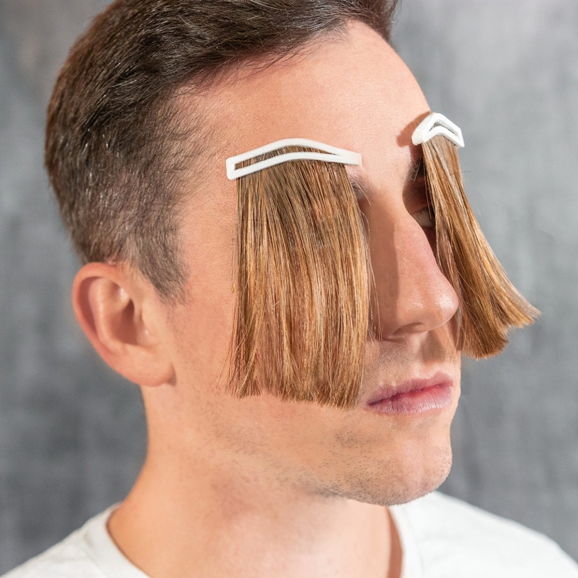 Matty wearing long brown hair extensions hanging from his eyebrows.