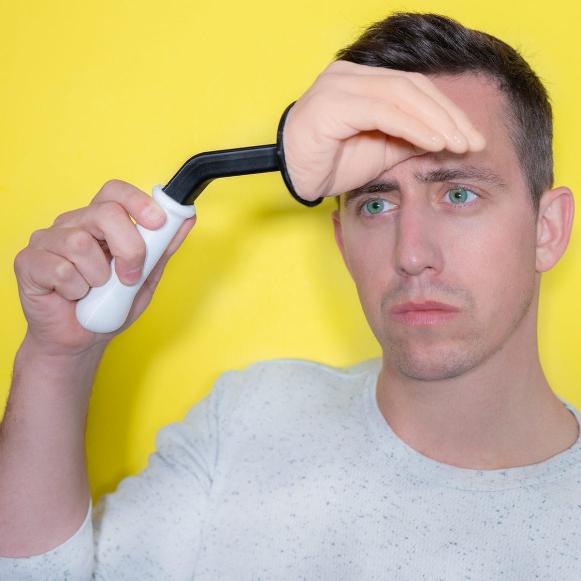 Matty holding a handle attached to a hand-shaped shade above his eyes.