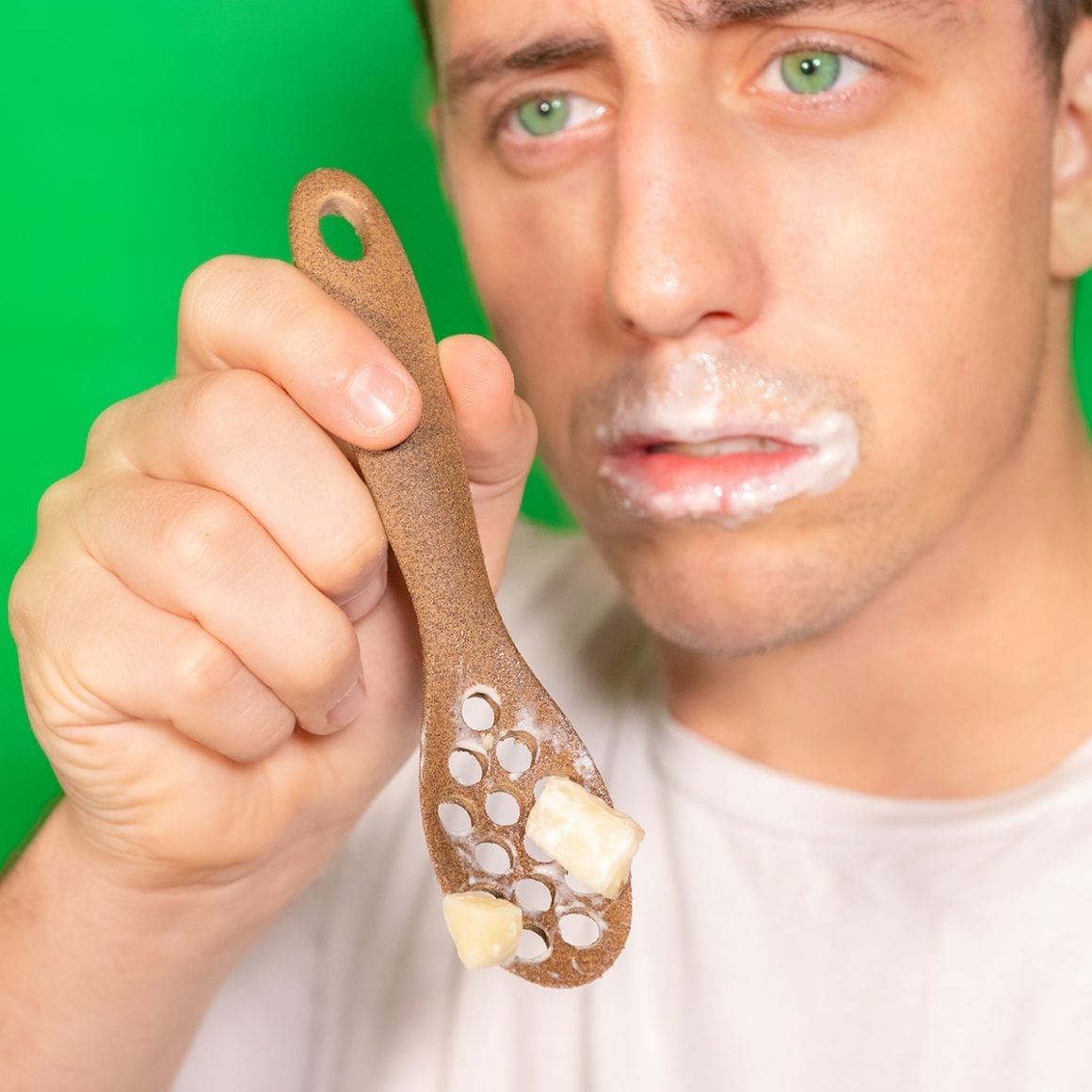 Matty holding a hole-filled spoon of cereal with milk around his mouth.