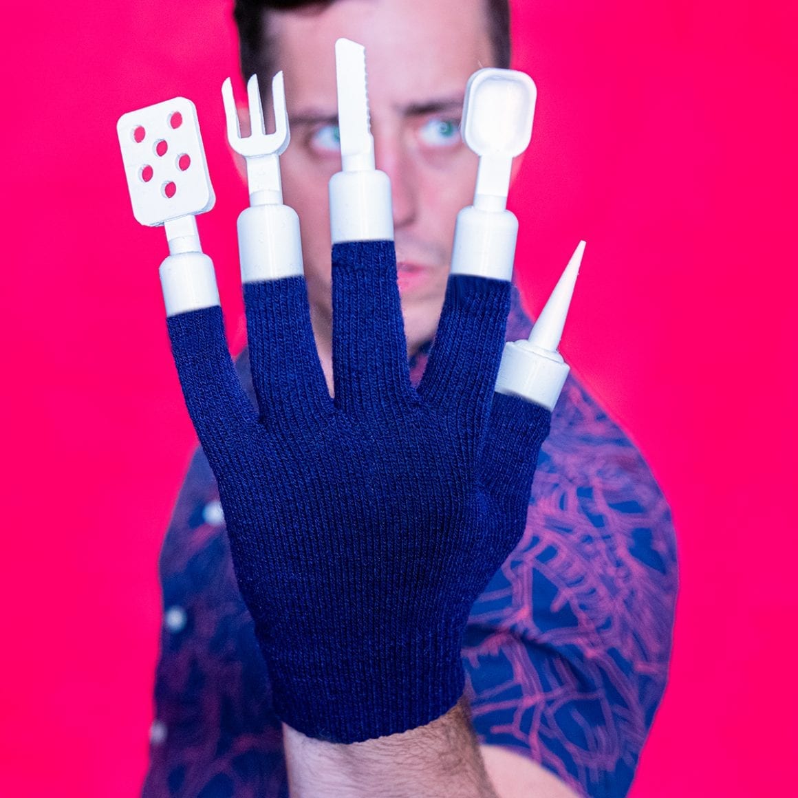 Matty displaying a glove tipped with a spatula, fork, knife, spoon and pointed skewer.
