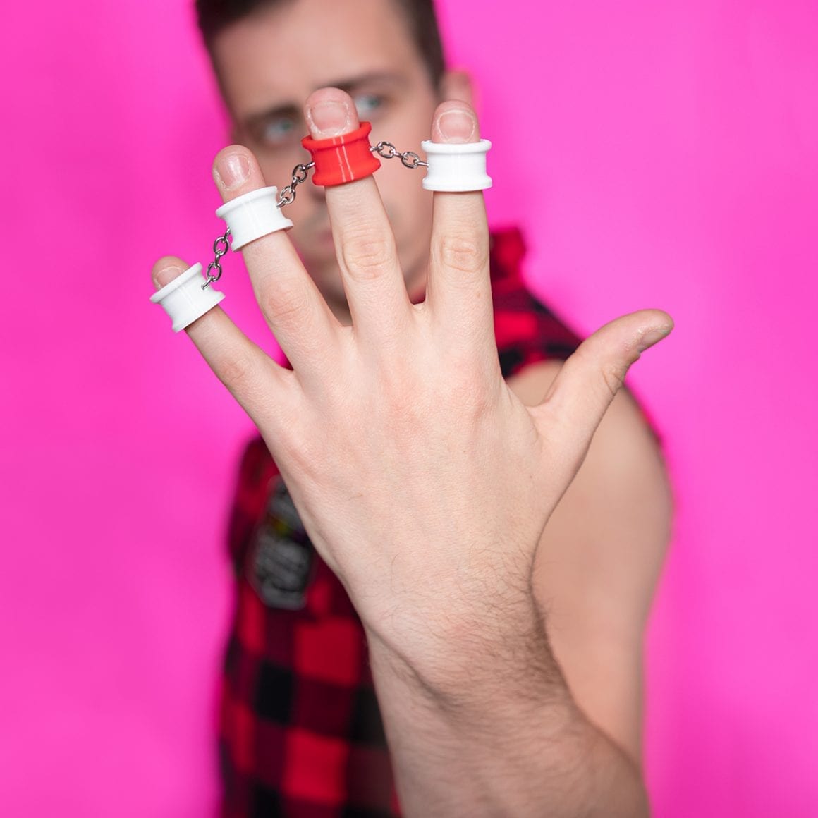 Matty holding up a hand fitted with rings connected across his fingers.