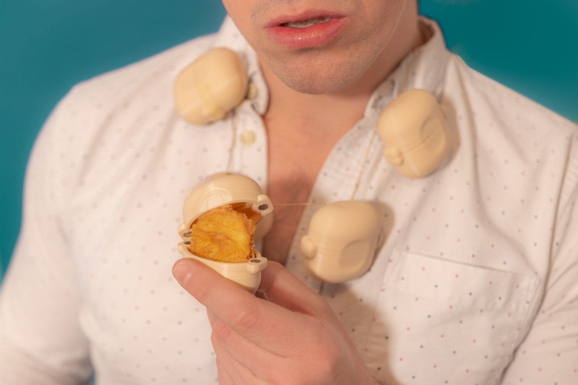 Matty opening one of several rounded necklace capsules to reveal a chicken nugget.